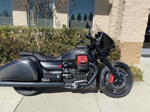 A black touring motorcycle parked beside a building.