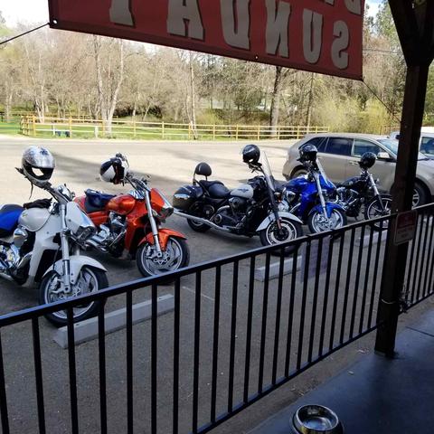 A row of motorcycles viewed from a shaded porch.