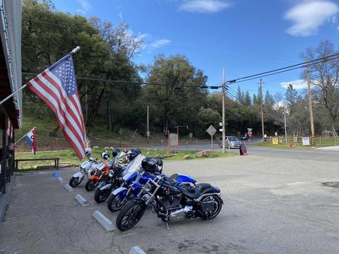 Motorcycles parked near a building with an American flag.
