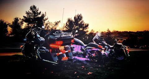 Motorcycles silhouetted against a colorful sunset.