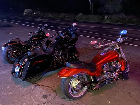 Two motorcycles parked under colored lights at night.