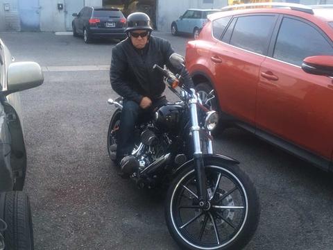 A helmeted rider seated on a motorcycle in a parking area.