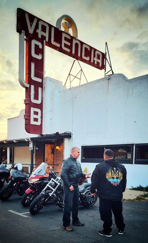 A person standing beside motorcycles outside a building.