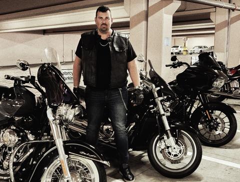 A person standing among motorcycles inside a building.