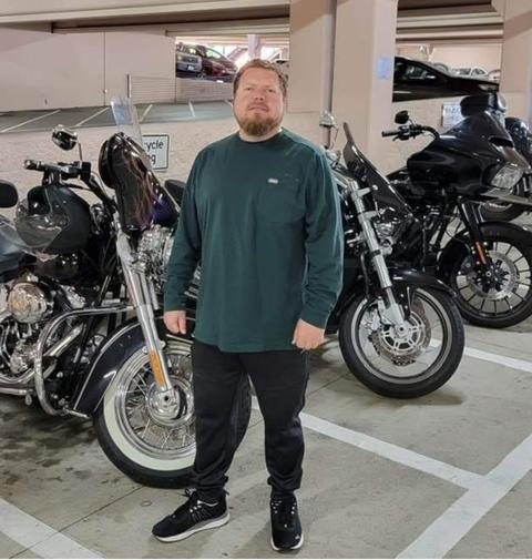 A person in a green shirt standing among motorcycles indoors.
