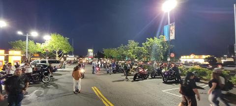 A wide view of motorcycles and people at a nighttime gathering.