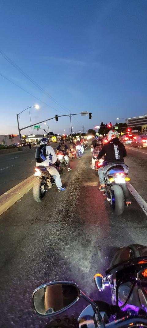 Motorcycles and people gathered outside around dusk.
