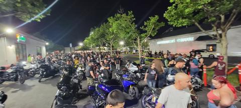 A crowd gathered beside rows of motorcycles after dark.