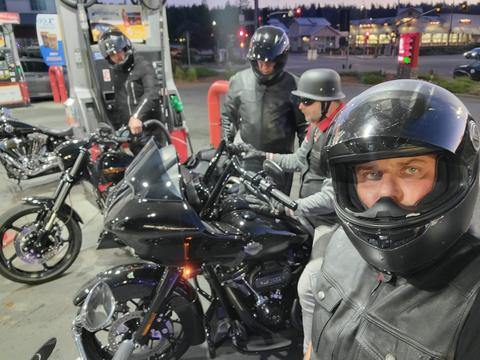 Helmeted riders taking a photo beside parked motorcycles.