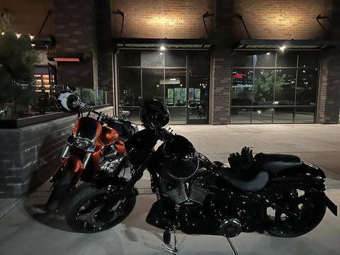 Motorcycles parked outside a glass-fronted entrance at night.