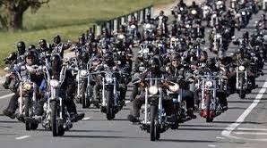 A large group of riders on motorcycles along a road.