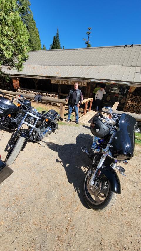 Motorcycles parked outside a shaded roadside building.