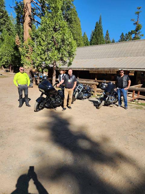 Another view of people and motorcycles outside a roadside building.