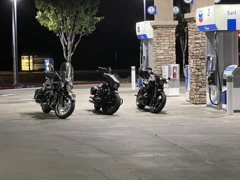 Three motorcycles parked at a fuel station after dark.