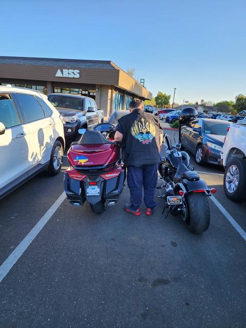 A rider standing among motorcycles in a parking lot.