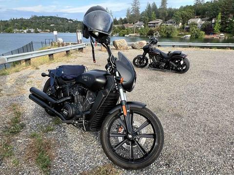 A black motorcycle parked beside a lakeside railing.