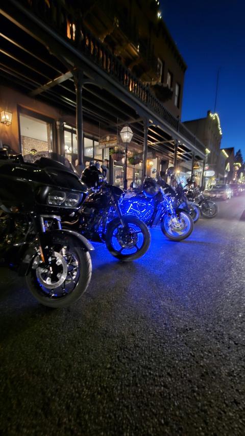 Motorcycles illuminated by blue lights along a street at night.