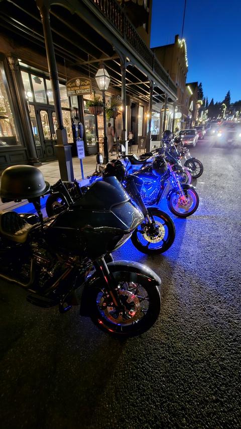 Another view of blue-lit motorcycles along a nighttime street.