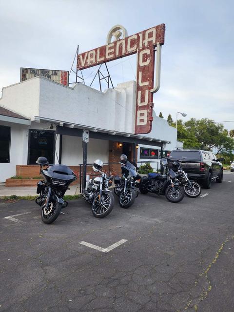 Motorcycles parked outside a building beneath a large sign.