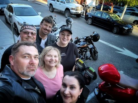 Friends gathered beside motorcycles for an outdoor group photo.