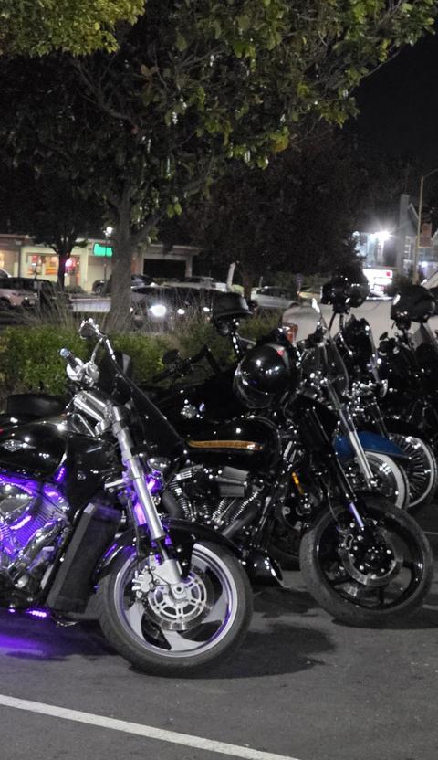 Motorcycles gathered outdoors after dark.