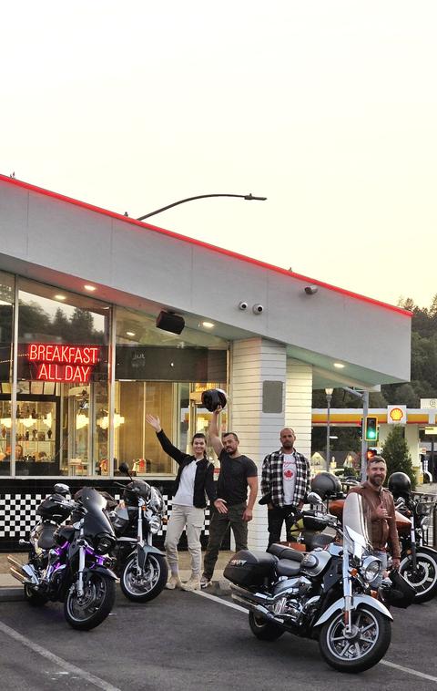 Riders gathered with motorcycles outside a roadside shop.
