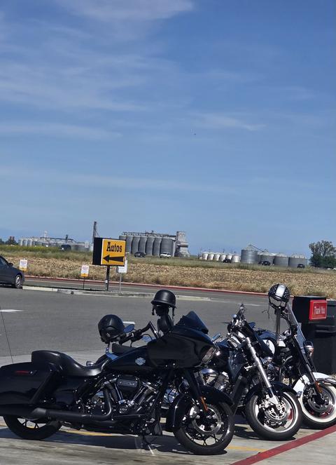 Motorcycles parked beside a road beneath a blue sky.