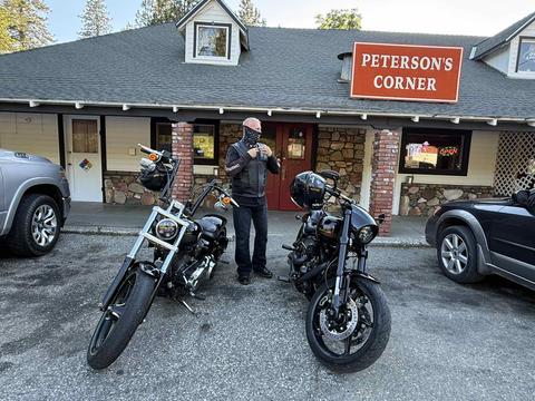 A rider standing beside two motorcycles outside a café.